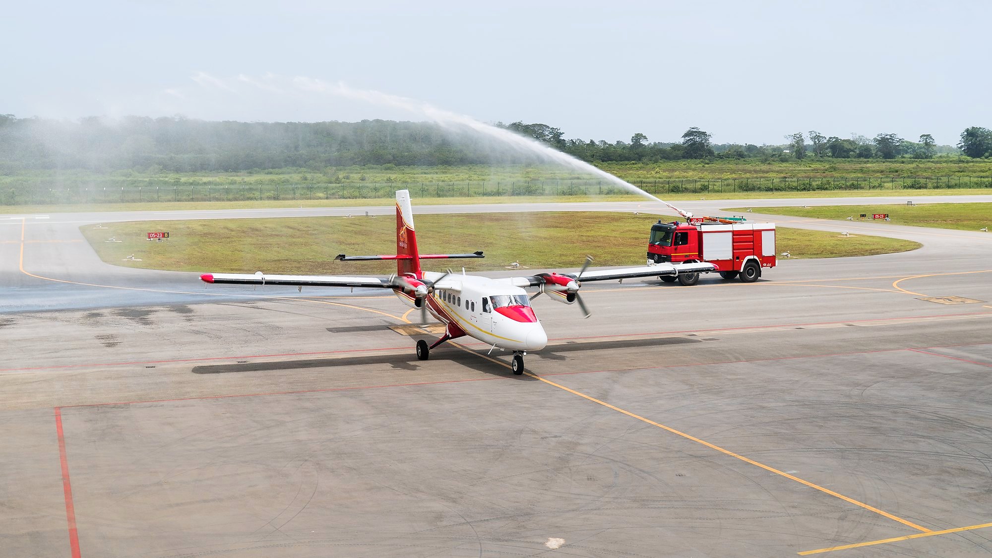 Two airport fire tenders arch jets of water over an aircraft taxiing at EAG, the water salute marking the first international commercial flight