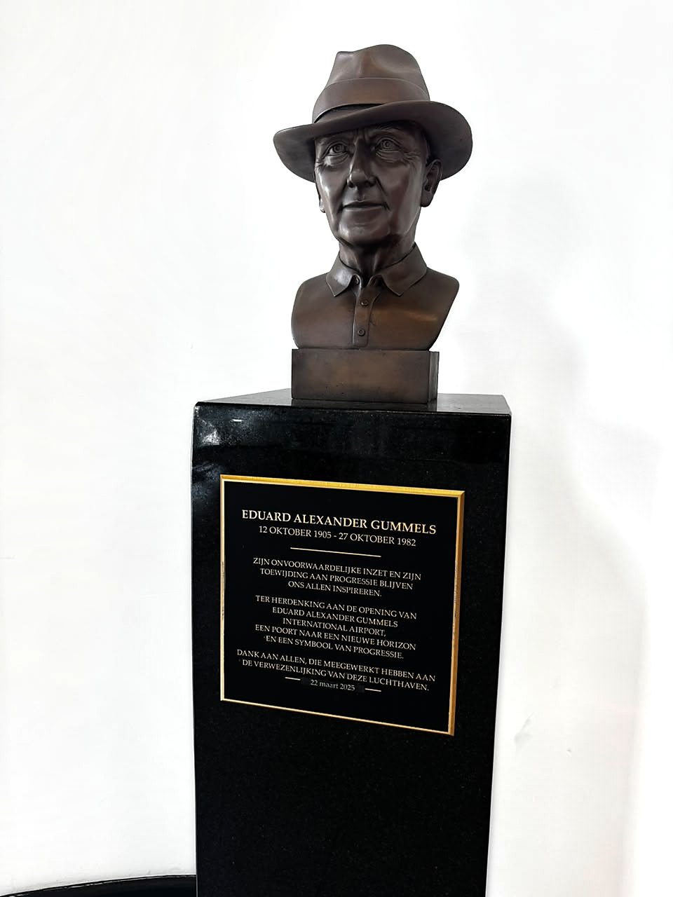 Bronze bust of Eduard Alexander Gummels, wearing a hat, on a black granite plinth with the memorial plaque