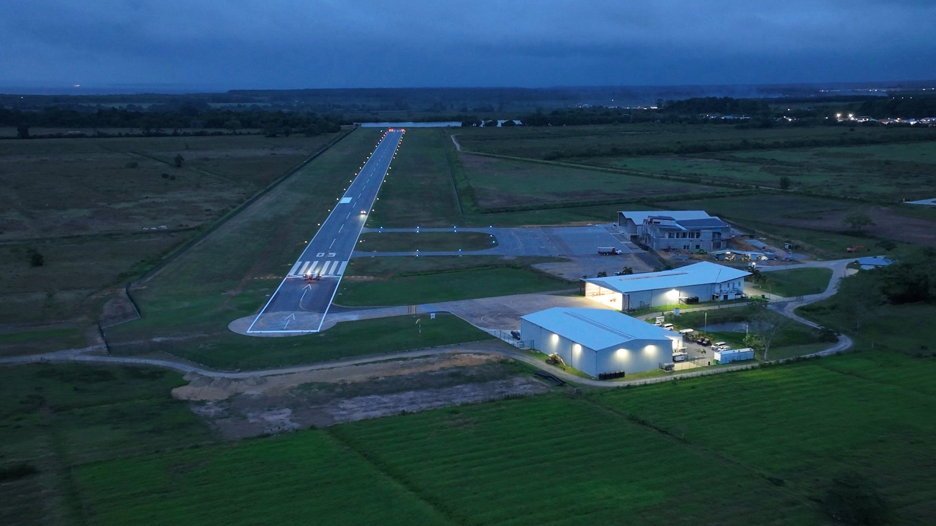 Blue-hour aerial of the EAG airfield with the runway lights burning