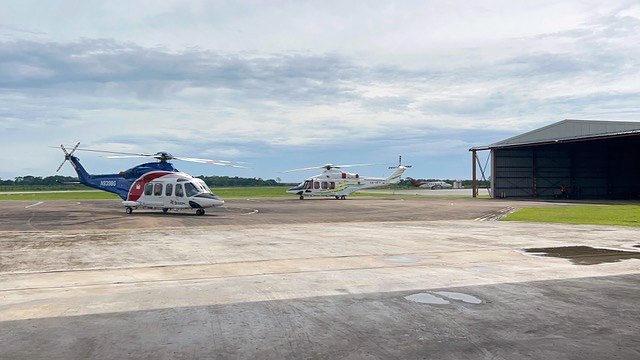 Two offshore helicopters parked in front of the EAG hangars